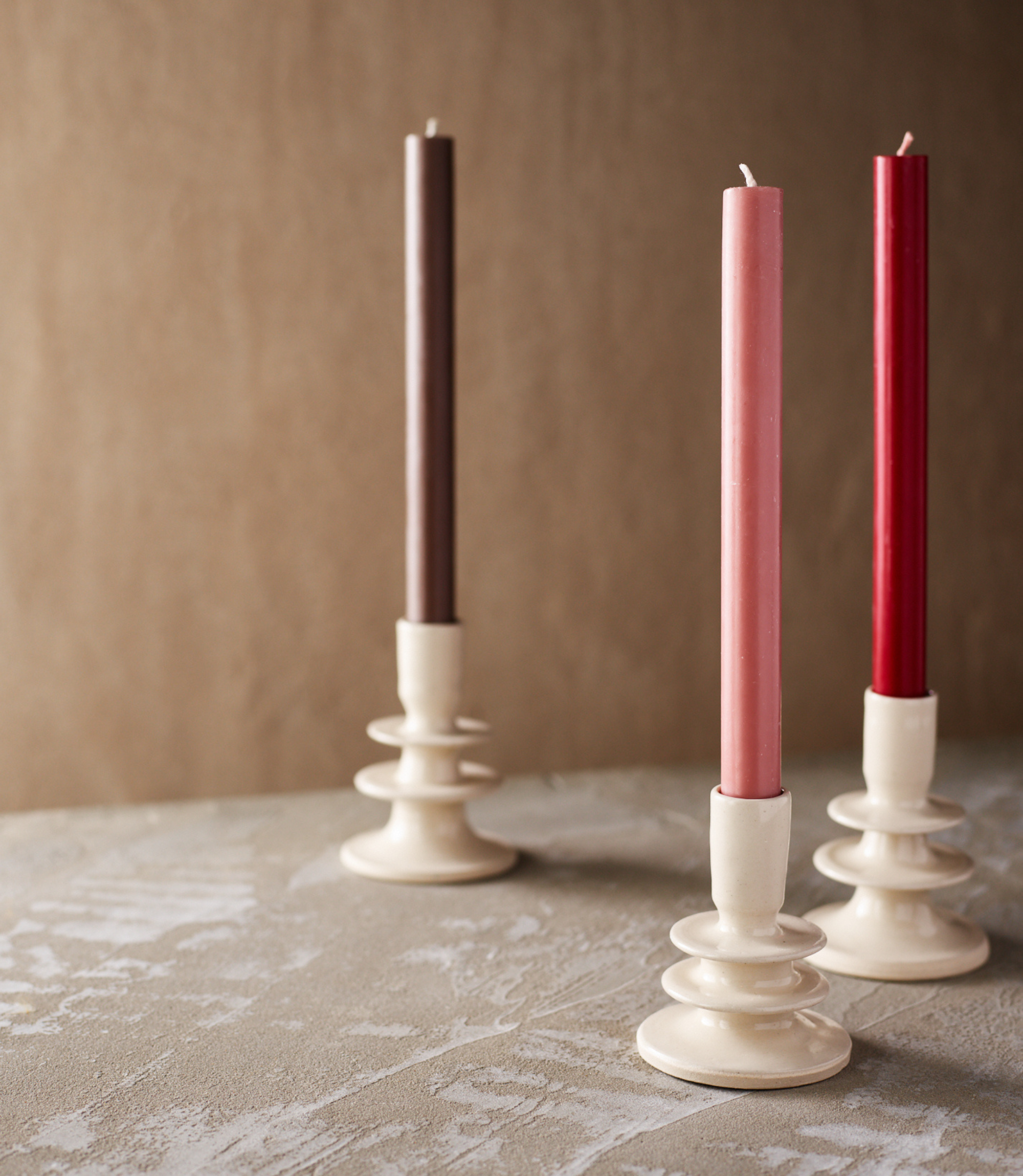 Colourful dinner candles in ceramic candlesticks