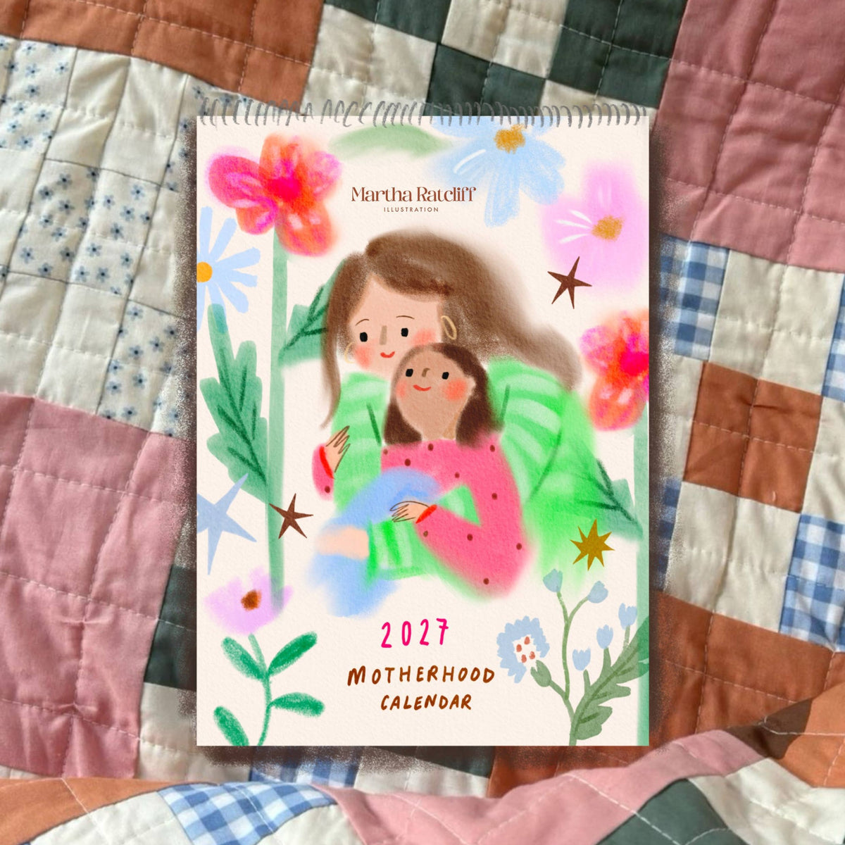 Martha Ratcliff 2027 Motherhood Calendar on a patchwork quilt